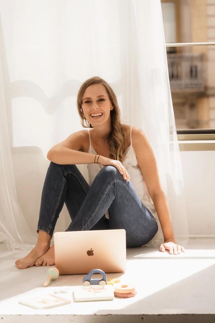 Jackie Lantzen sitting by the window with her laptop, smiling