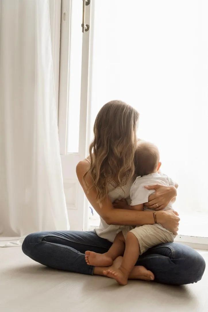A mother holding her baby by the window